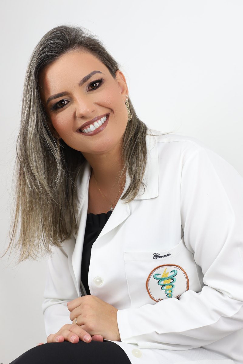 Glennia Goulart de jaleco, em seu consultório